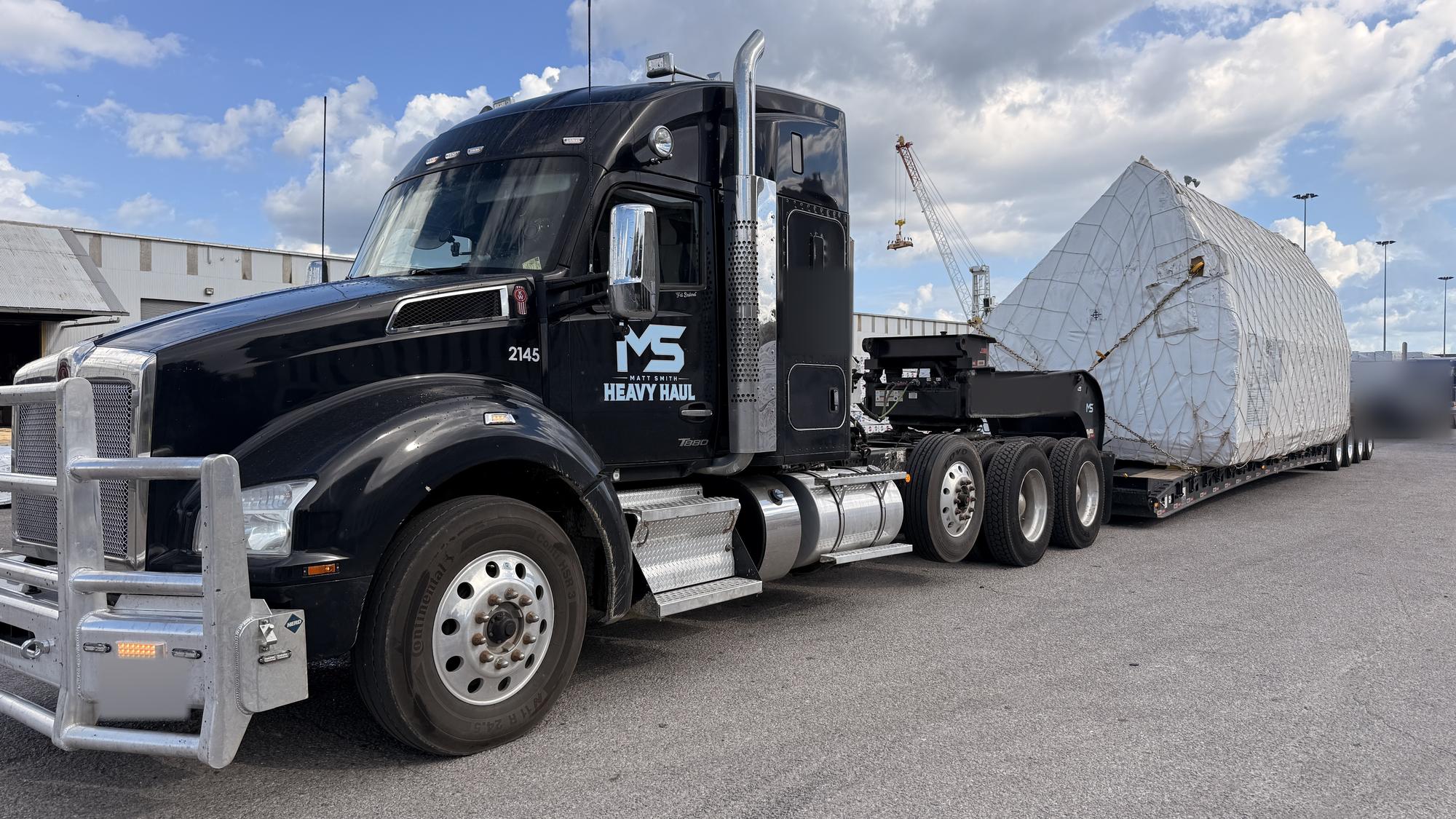 MS Heavy Haul tractor and multi-axle lowboy staged in the yard with a wrapped oversize load