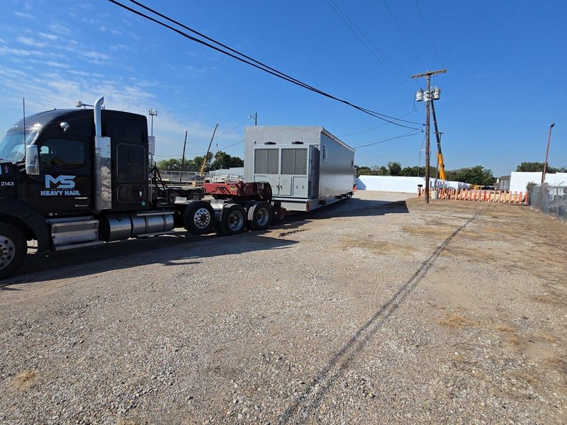 MS Heavy Haul truck 2143 pulling a data center cooler module on a stretch RGN out of a gravel yard in Irving, Texas