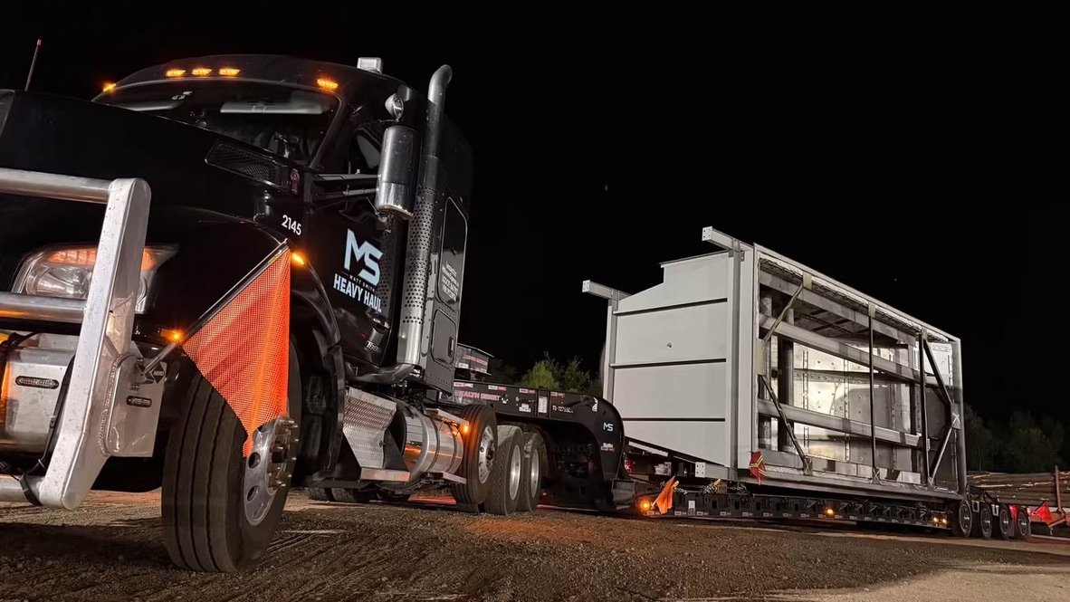 Low-angle night view of truck 2145 hauling a large steel structure