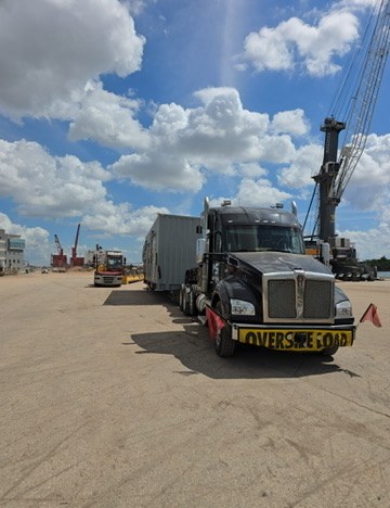 MS Heavy Haul truck with oversize load banner at a port with cranes